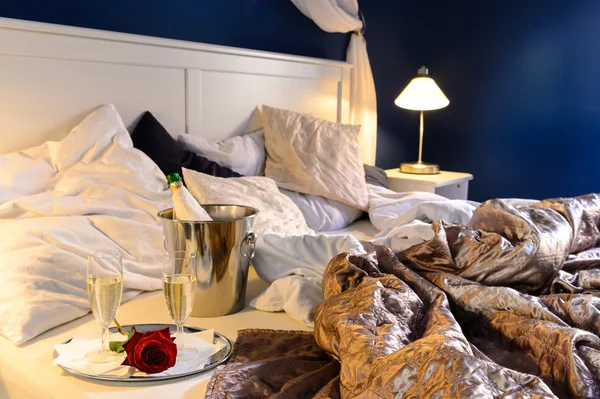 Romantic bedroom rumpled covers hotel champagne bucket — Stock Photo, Image