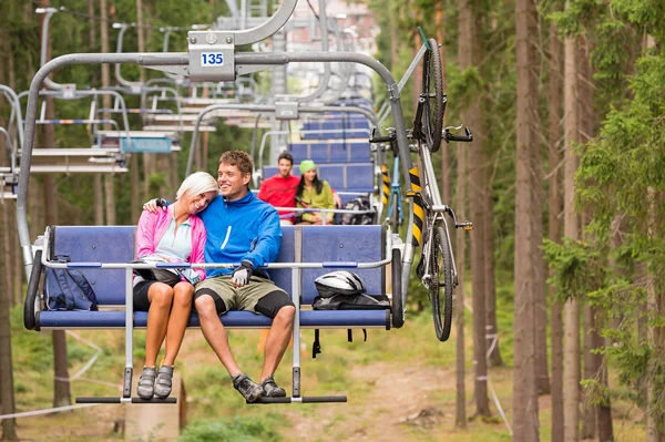Carefree couple traveling by chair lift wood — Stock Photo, Image
