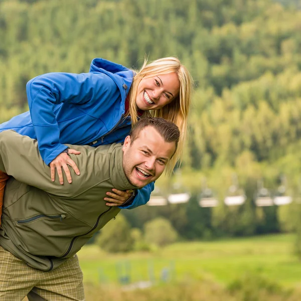 Couple having piggyback ride outside green nature — Stock Photo, Image