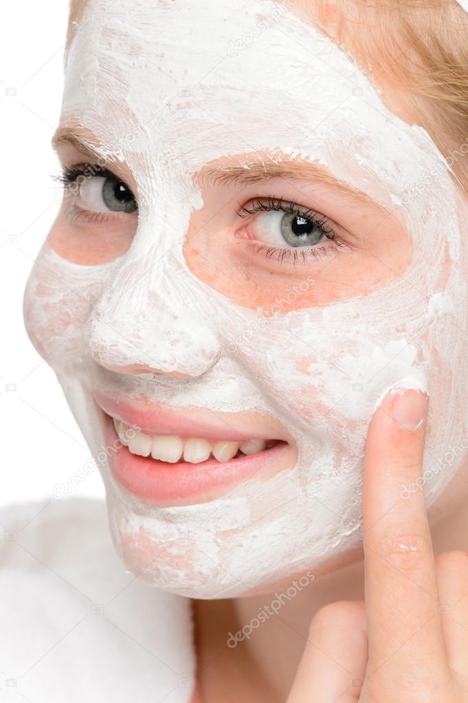 Young teen girl putting facial mask cream Stock Photo by