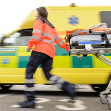 Running blurry paramedic woman pulling gurney