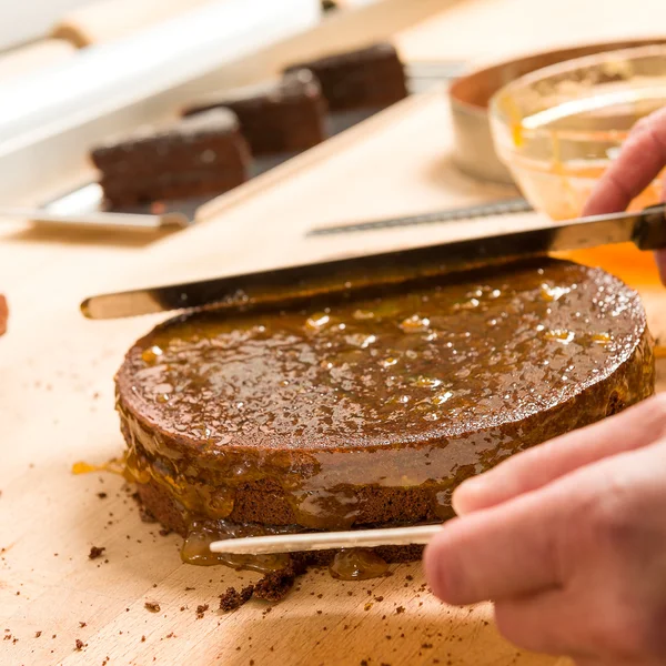 Mãos de cozinheiro em ação espalhando bolo — Fotografia de Stock