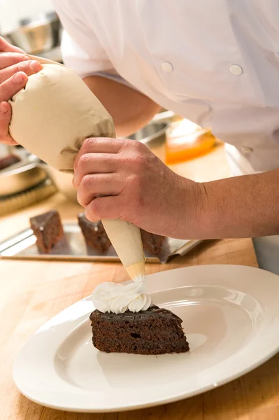 Cook decorating cake with whipped cream — Stock Photo, Image