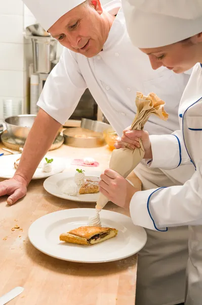 Жіночий шеф-кухар прикрашає торт зі збитими вершками — стокове фото