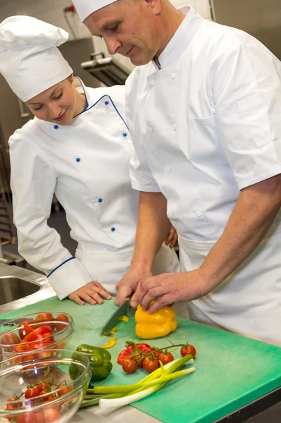 Apprentice learning cutting vegetables from chef — Stock Photo, Image