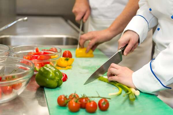 Close up of chefs cutting vegetables in hotel's kitchen