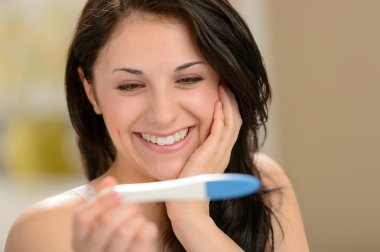 Delighted woman holding pregnancy test clipart