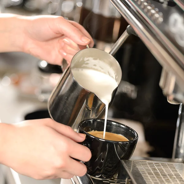 Empregada de mesa mãos derramando leite fazendo cappuccino — Fotografia de Stock
