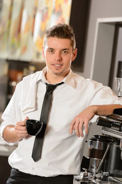 Garçom atraente inclinado na máquina de café expresso — Fotografia de Stock