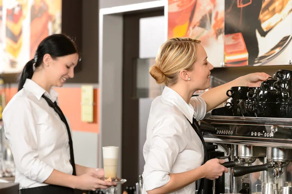 两个女服务员品尝咖啡机 免版税图库照片