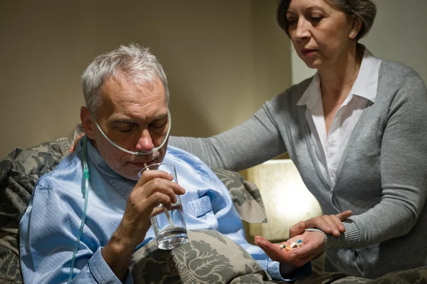 Hombre mayor tomando medicamentos con agua —  Fotos de Stock