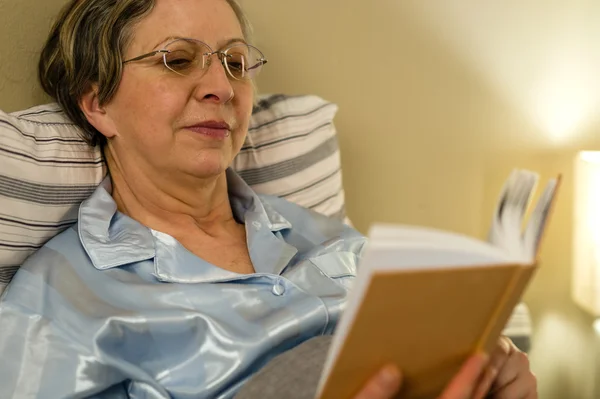 Betagte Frau liest Buch in Wohnheim — Stockfoto