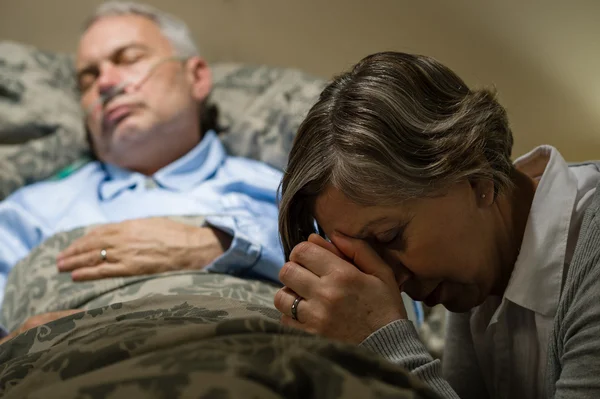 Ongemakkelijk senior vrouw bidden voor zieke man Rechtenvrije Stockfoto's