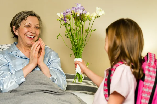 Chica dando ramo de flores a la abuela Imagen De Stock