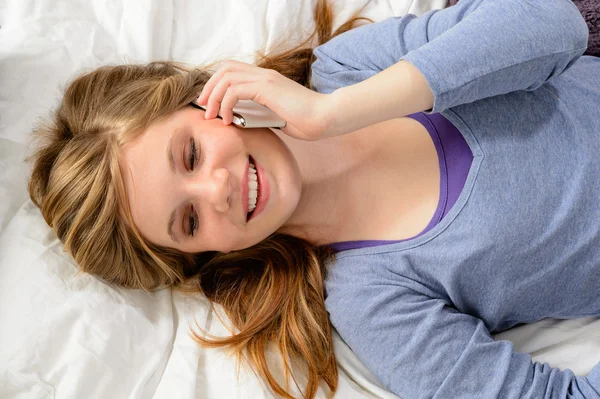 Chica acostada en la cama hablando por teléfono — Foto de Stock