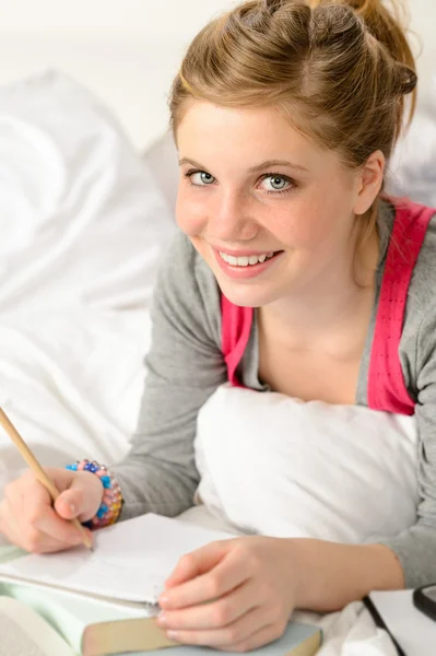 Leende flickan förbereder sig för tentor i sängen — Stockfoto