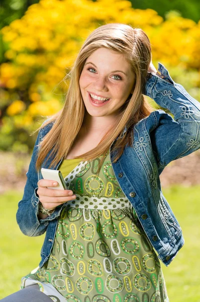 Parmantig vrouwelijke tiener texting in het park — Stockfoto