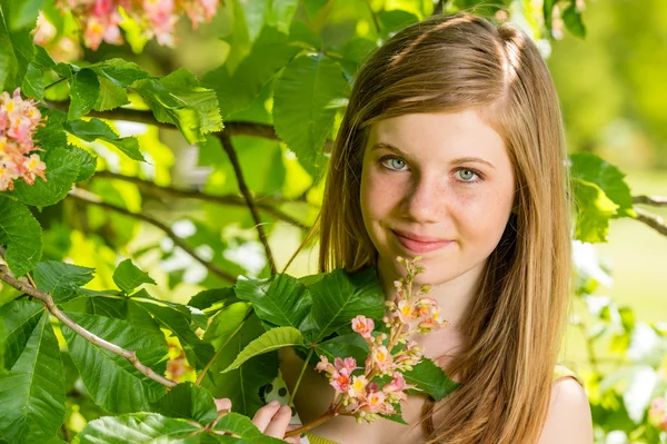 Menina na luz do sol cheiro árvore flor — Fotografia de Stock