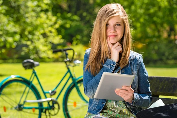 Fundersam tonåring i park med tablett — Stockfoto