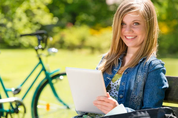 Unga flicka med hjälp av tablet PC i park — Stockfoto