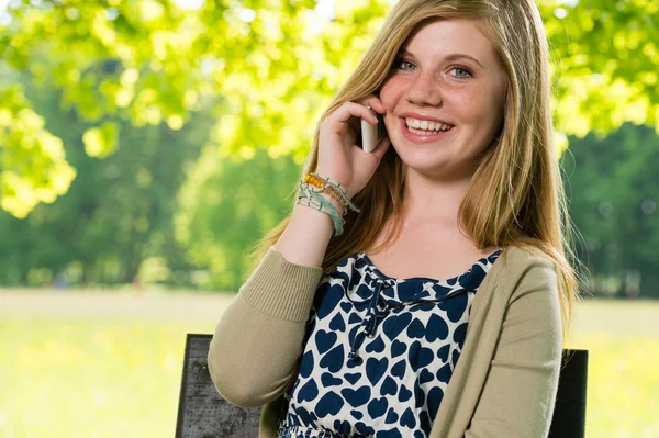 Leende ung flicka med sin mobiltelefon — Stockfoto