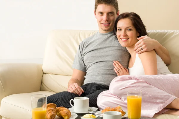 Casal alegre sentado no sofá antes do café da manhã — Fotografia de Stock