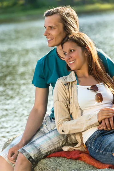 Sonriente adolescente pareja sentado en una roca —  Fotos de Stock