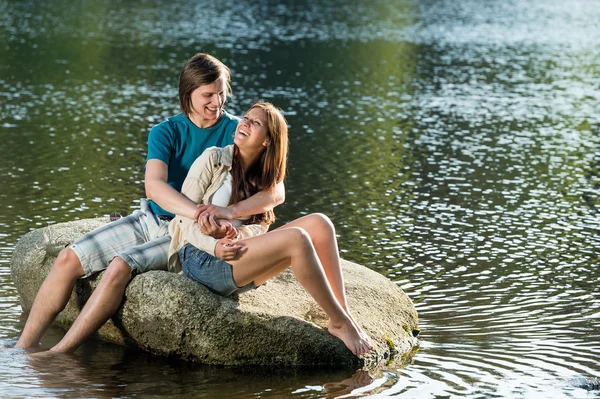 Couple assis sur le rocher au bord du lac — Photo