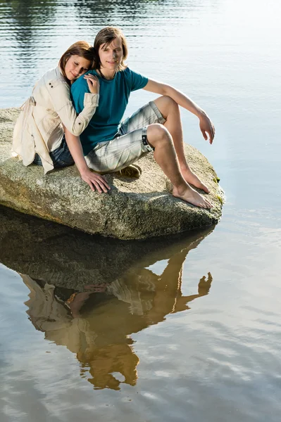Coppia seduta su roccia tramonto sul lago — Foto Stock