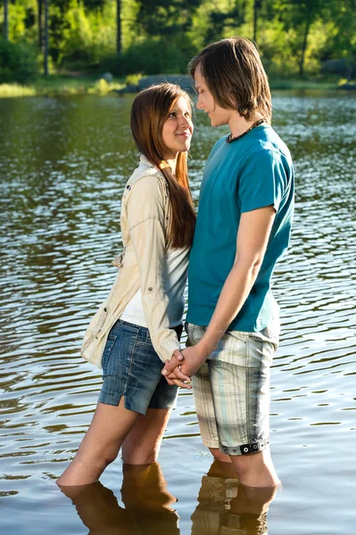 Teens standing in water and holding hands — Stock Photo, Image