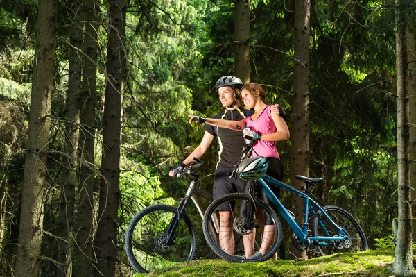 Sorrindo jovens ciclistas de pé e apontando — Fotografia de Stock