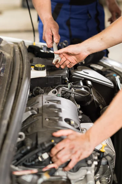 Meccanico di auto passando una chiave inglese al collega — Foto Stock