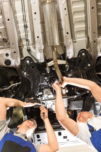 Reparadores caucásicos trabajando bajo el automóvil — Foto de Stock