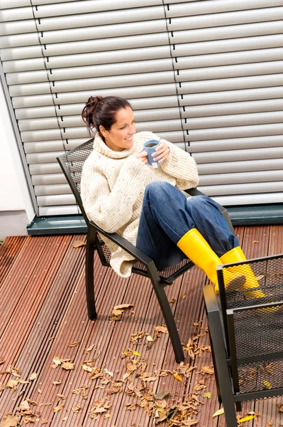 Young woman sitting drinking tea fall patio — Stockfoto