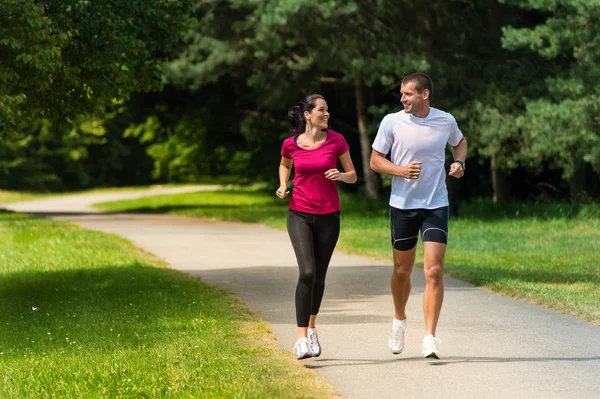 Alegre pareja amigos corriendo en parque Fotos De Stock