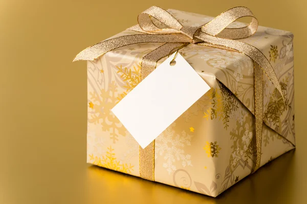 Kerstcadeau met gouden lint en lege tag — Stockfoto