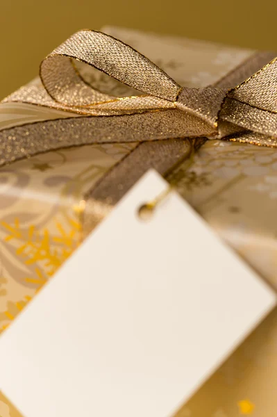 Presente de Natal com fita de ouro etiqueta em branco — Fotografia de Stock