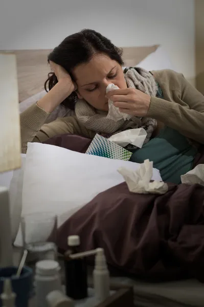Hasta bir kadın yatakta hapşırma grip ile — Stok fotoğraf