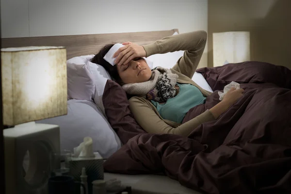 Молодая женщина лежит больной в постели холодно — стоковое фото