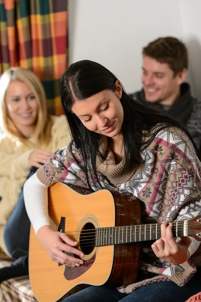 Młodzi przyjaciele w domek zimą grać na gitarze — Zdjęcie stockowe