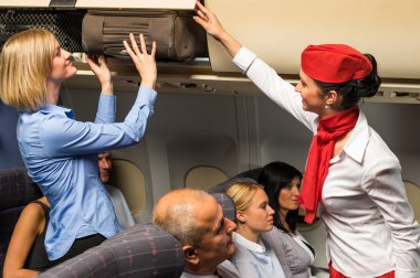Flight attendant help passenger with luggage cabin