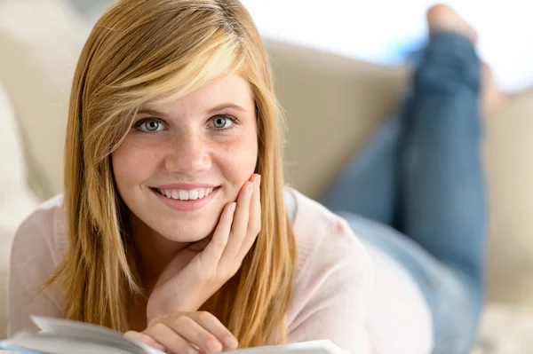 Smiling student girl read book lying sofa — Stock Photo, Image