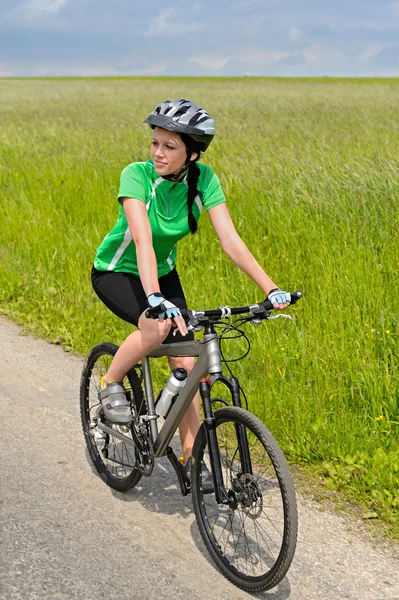 Mulher de bicicleta na estrada rural dia ensolarado — Fotografia de Stock