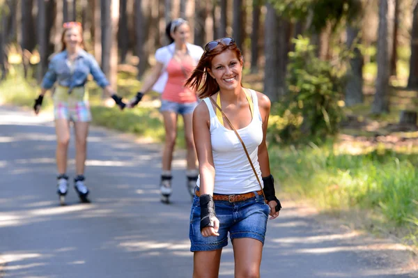 Young woman roller skating outdoors with friends — Stock Photo, Image