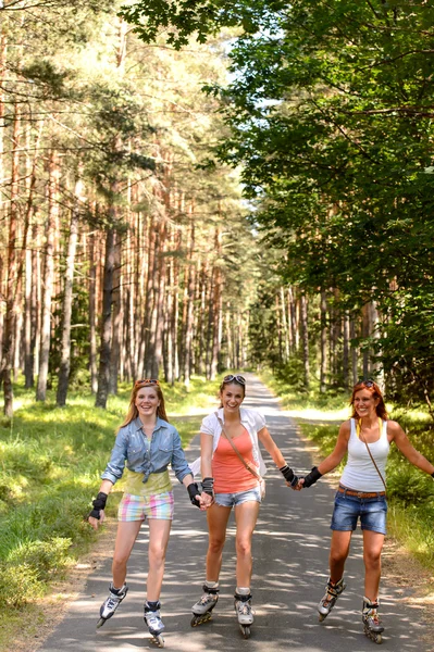 Drie vrienden rolschaatsen buiten houden handen — Stockfoto