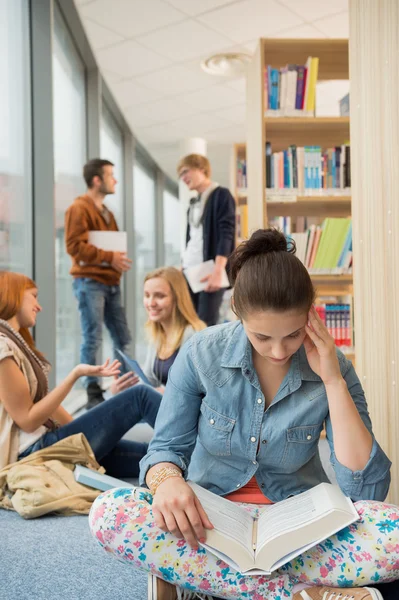 Chica leyendo libro en la biblioteca de la universidad — Foto de Stock