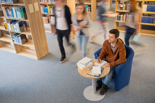 Estudante escrevendo notas no movimento de borrão da biblioteca — Fotografia de Stock