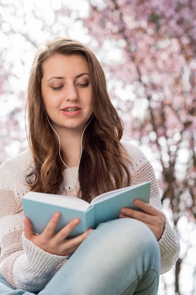 Estudiante leyendo libro cerca de árbol floreciente — Foto de Stock