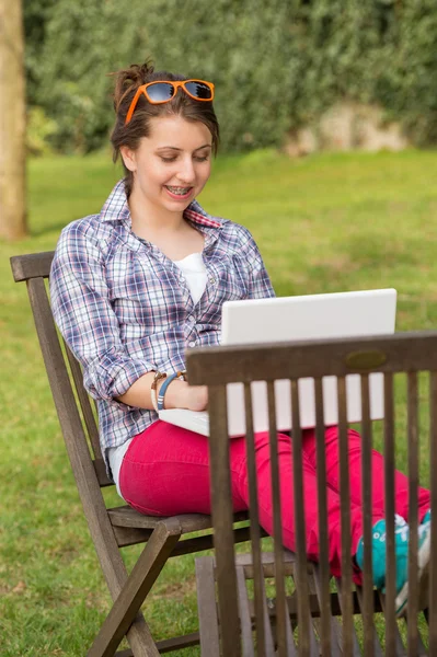 Chica usando portátil sentado en el parque — Foto de Stock