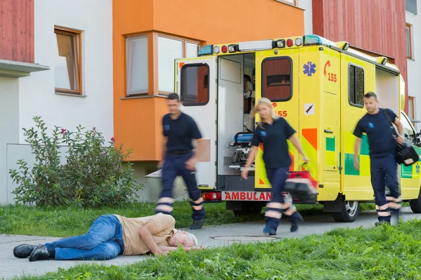 Emergency team running to unconscious man — Stock Photo, Image